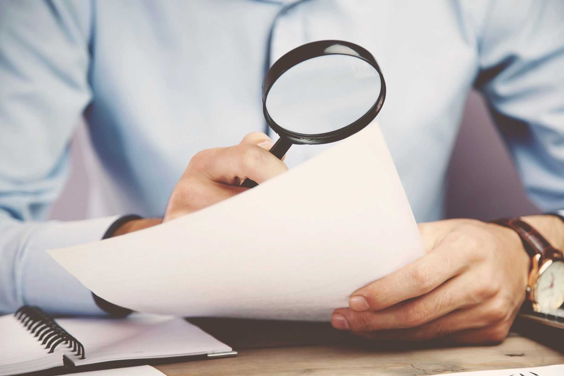 Handwriting expert using magnifying glass on document