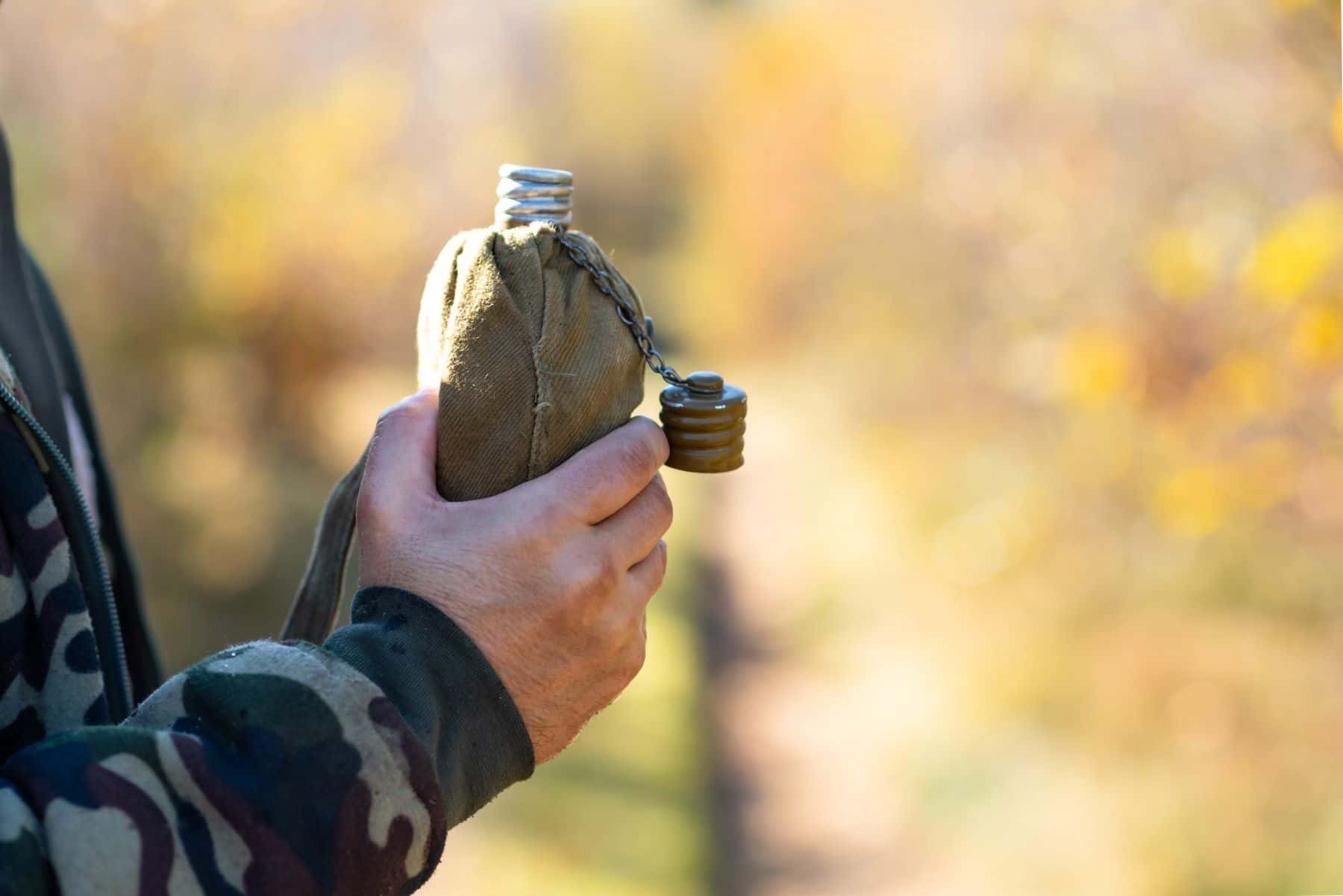 Military person holding water canteen