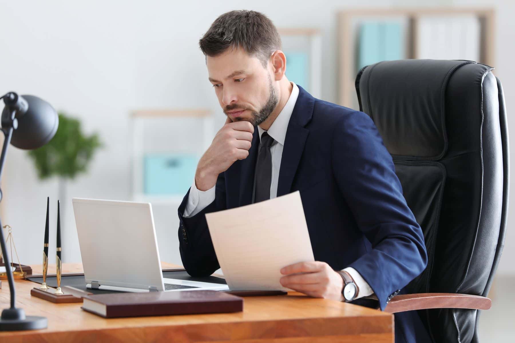 Attorney on laptop computer holding paper